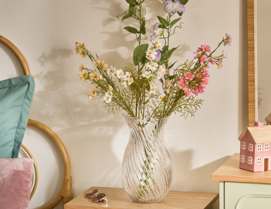 Enfoque en un jarrón transparente sobre una mesita de noche de la colección Blossom de Atmosphera lleno de un ramo rosa y blanco.