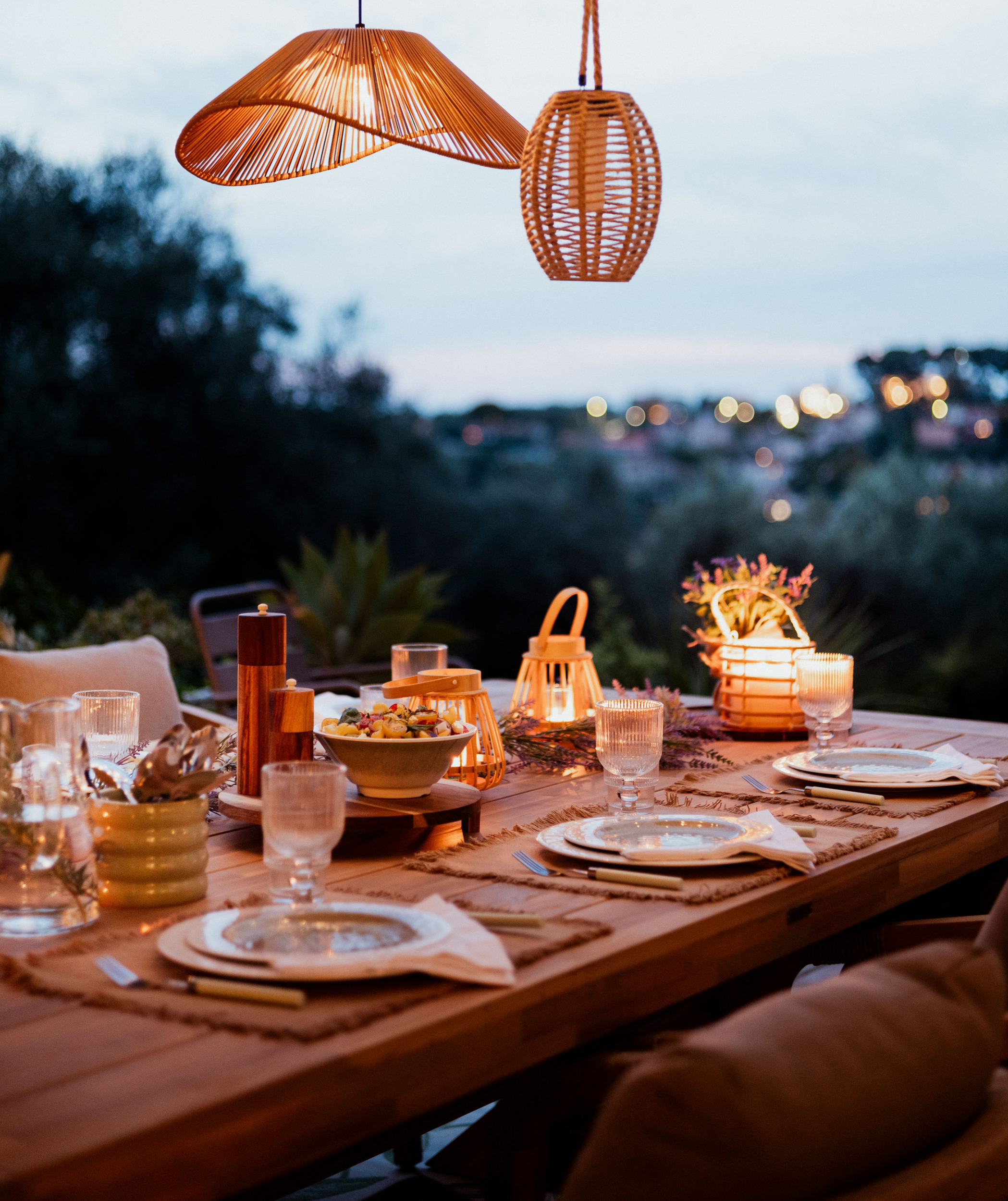 table extérieure déco esprit guinguette avec lanternes lumineuses et suspensions en rotin ambiance soirée d’été