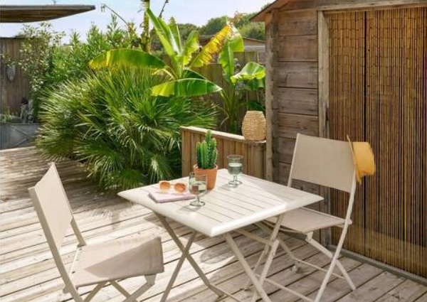 table et chaises pliantes Hespéride sur terrasse en bois ambiance guinguette avec cabane et végétation