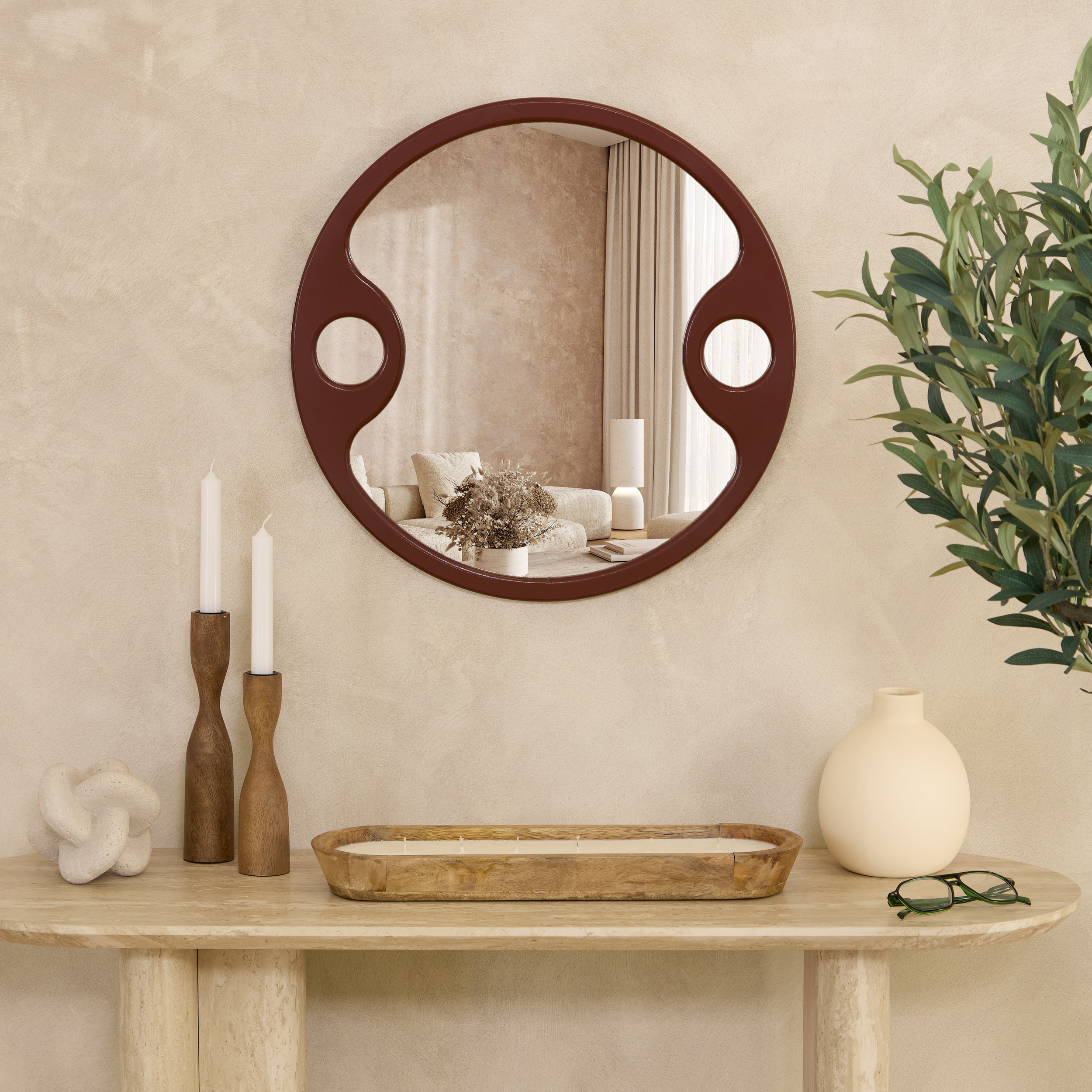 miroir rond design terracotta au-dessus d’une console en pierre dans une décoration contemporaine chaleureuse