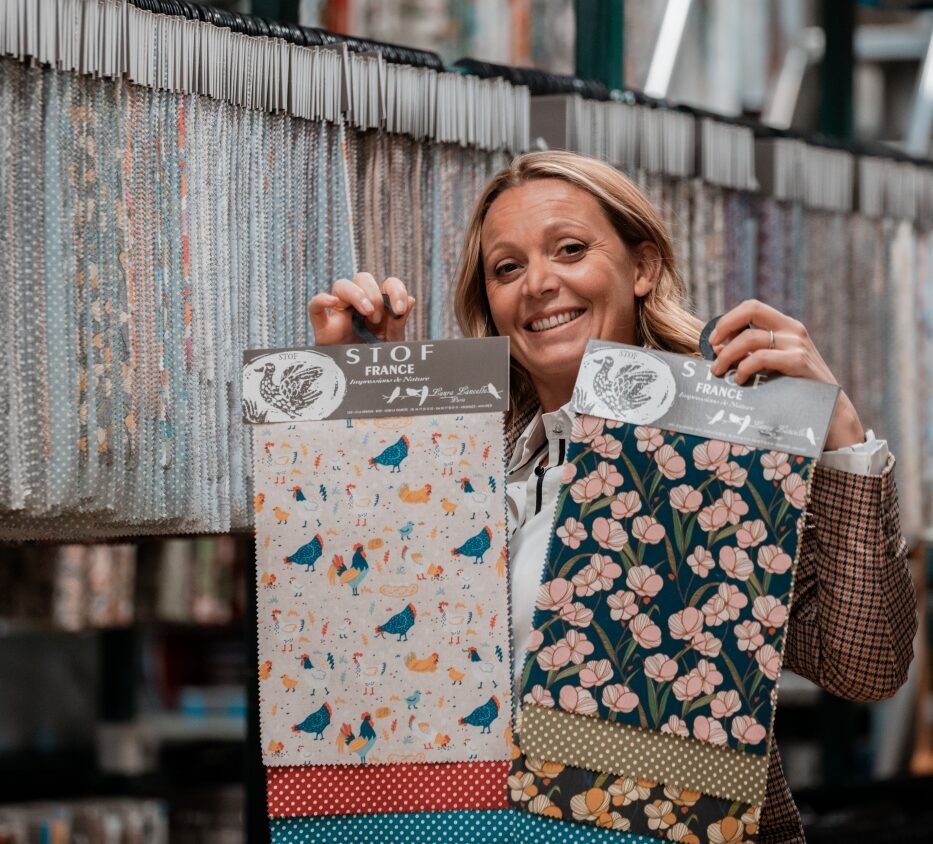 Bertille Pelardy présentant des échantillons de tissus STOF devant les collections textiles de l'entreprise spécialisée dans le tissu d'ameublement
