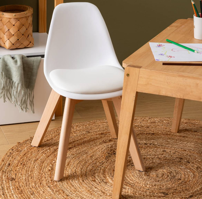 silla infantil blanca con patas de madera junto a una mesa de actividades en una habitación infantil de estilo escandinavo